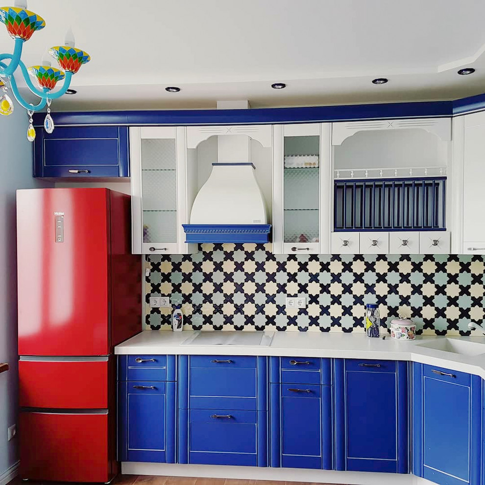 This is an example of a small asian l-shaped separate kitchen in Moscow with an undermount sink, recessed-panel cabinets, blue cabinets, solid surface benchtops, multi-coloured splashback, mosaic tile splashback, coloured appliances, porcelain floors, no island, beige floor and white benchtop.