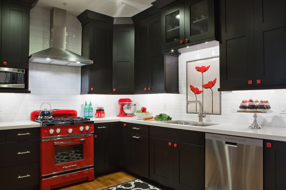 This is an example of a large eclectic l-shaped eat-in kitchen in Atlanta with flat-panel cabinets, black cabinets, quartz benchtops, white splashback, ceramic splashback, coloured appliances, a double-bowl sink, medium hardwood floors and no island.