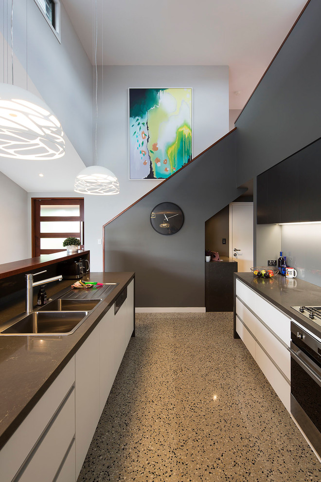 Design ideas for a mid-sized contemporary galley eat-in kitchen in Brisbane with a drop-in sink, flat-panel cabinets, white cabinets, quartz benchtops, metallic splashback, mirror splashback, black appliances, concrete floors, with island, grey floor and brown benchtop.
