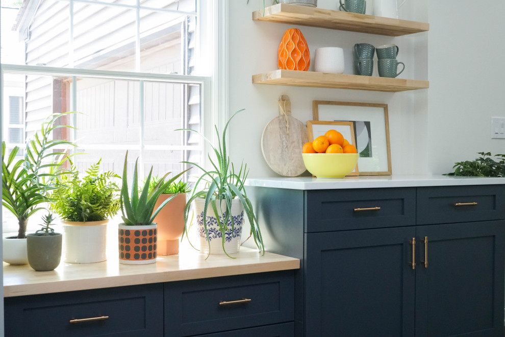 Inspiration for a mid-sized eclectic l-shaped eat-in kitchen in Detroit with a farmhouse sink, shaker cabinets, blue cabinets, orange splashback, ceramic splashback, stainless steel appliances, a peninsula and white benchtop.