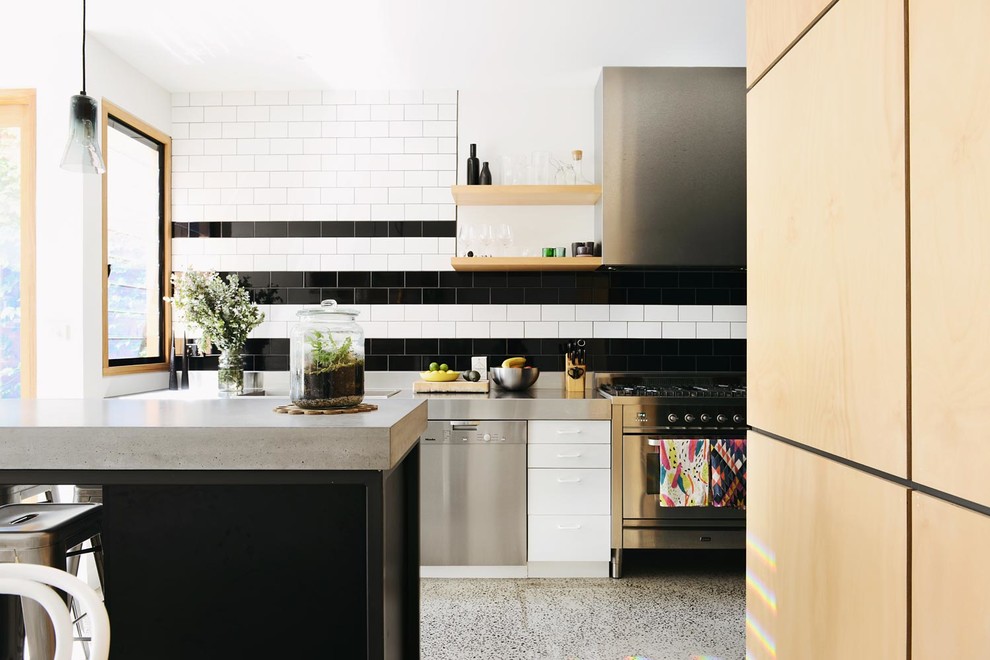 Photo of a contemporary kitchen in Melbourne with concrete benchtops, flat-panel cabinets, multi-coloured splashback, subway tile splashback and stainless steel appliances.
