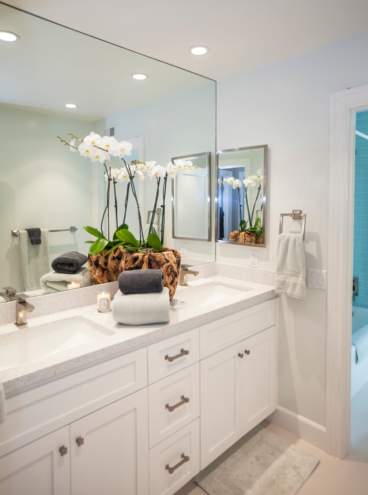 Inspiration for a large beach style bathroom in Orange County with an undermount sink, white cabinets, engineered quartz benchtops, white walls, limestone floors and recessed-panel cabinets.