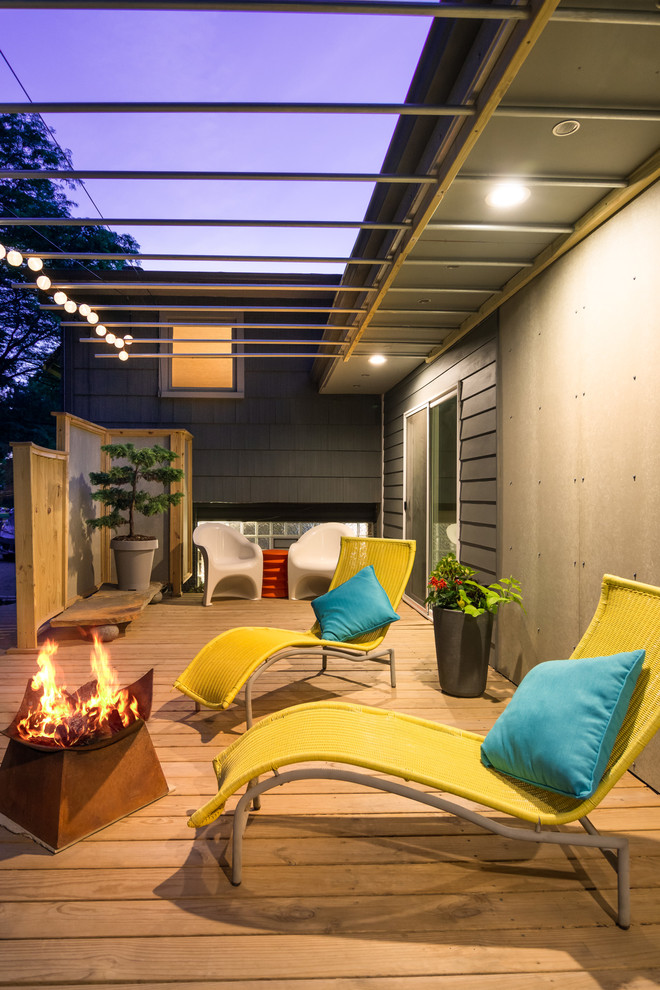 This is an example of a small contemporary backyard deck in Detroit with a fire feature and a pergola.