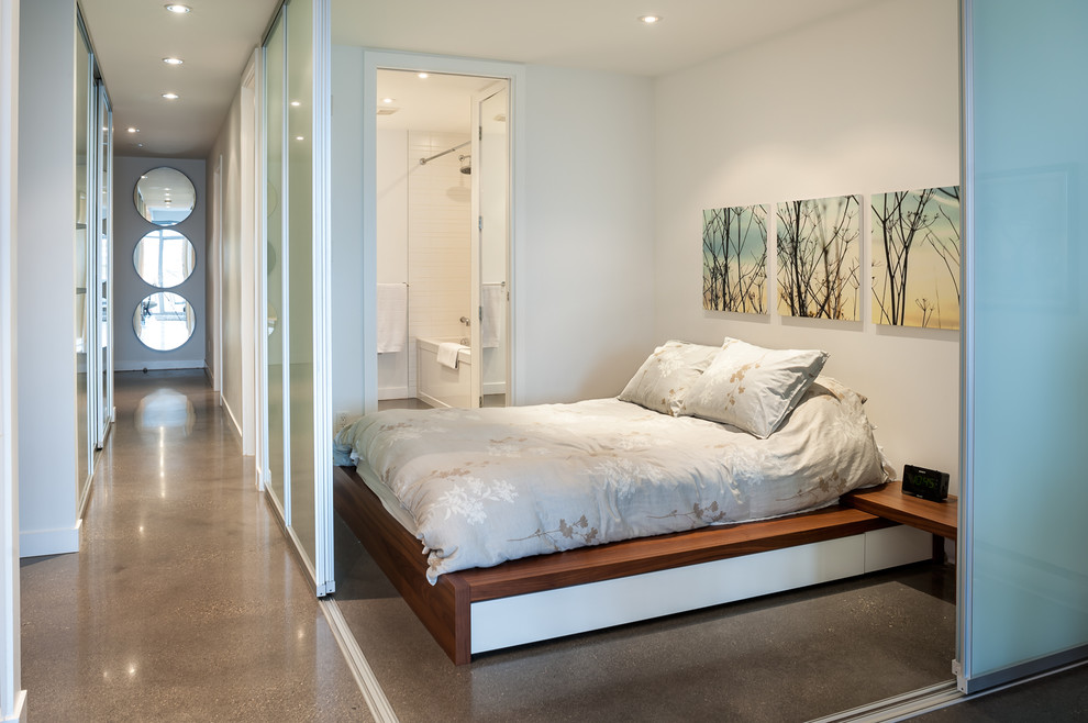 Contemporary bedroom in Vancouver with white walls and concrete floors.