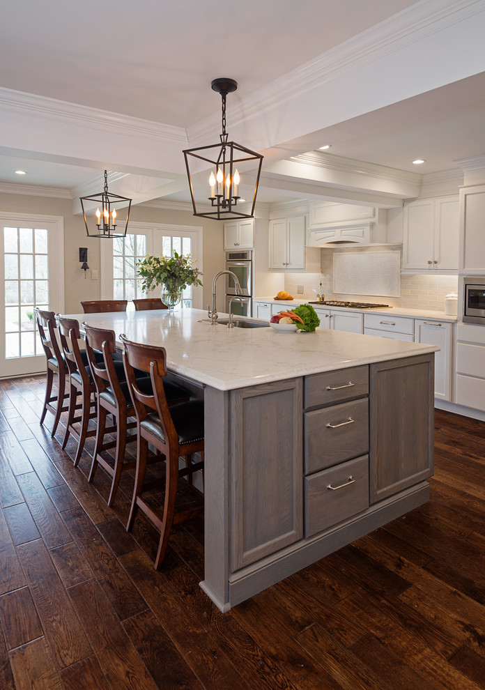Huge transitional l-shaped medium tone wood floor open concept kitchen photo with flat-panel cabinets, white cabinets, marble countertops, gray backsplash, porcelain backsplash, paneled appliances and an island