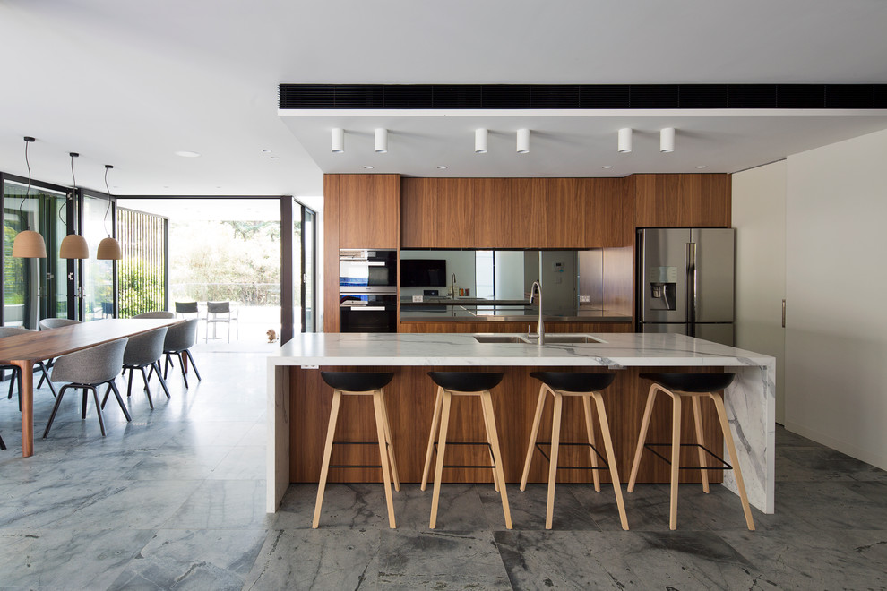 Design ideas for a large contemporary galley open plan kitchen in Sydney with an undermount sink, marble benchtops, mirror splashback, stainless steel appliances, with island, flat-panel cabinets and medium wood cabinets.