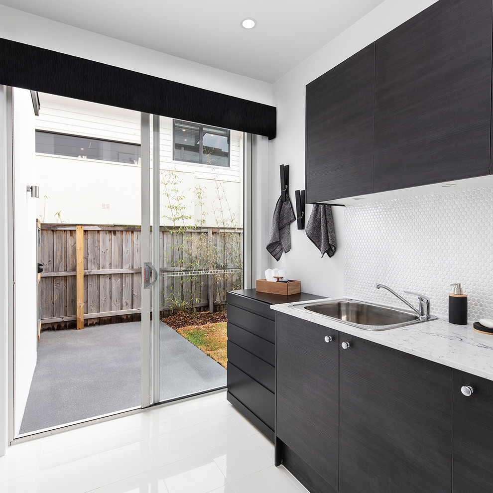Inspiration for a mid-sized contemporary galley dedicated laundry room in Wollongong with a double-bowl sink, shaker cabinets, dark wood cabinets, marble benchtops, white walls, ceramic floors, white floor and white benchtop.
