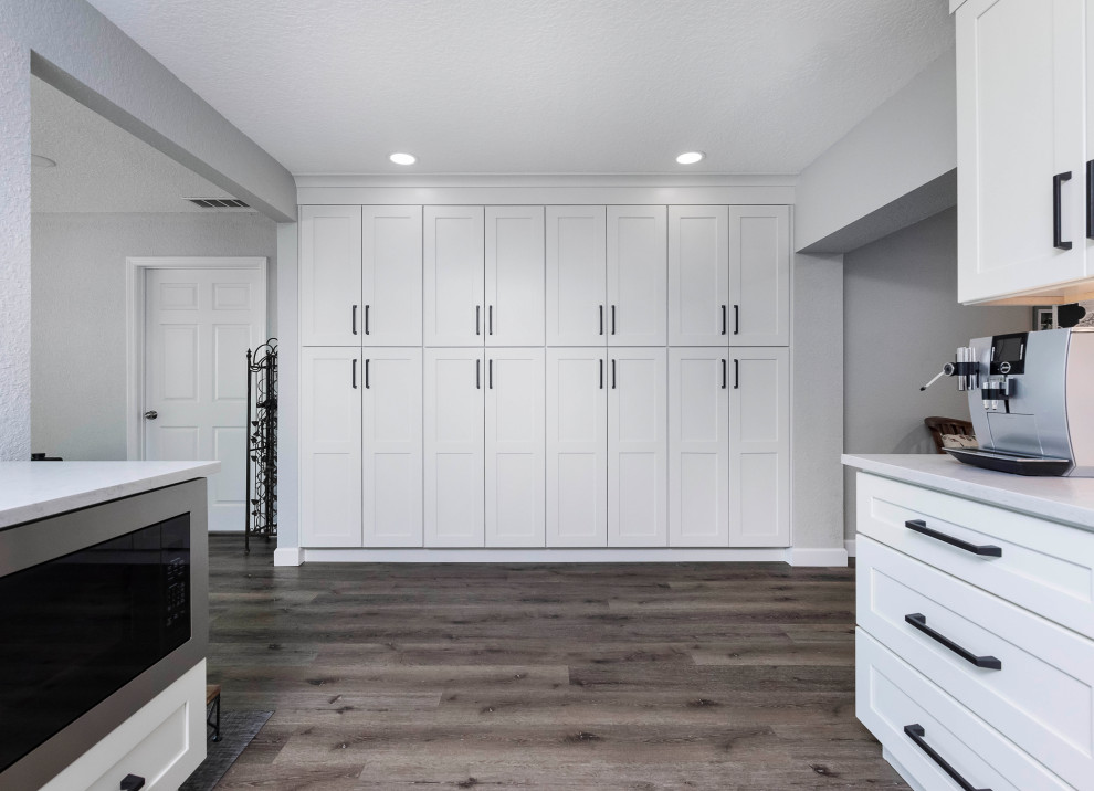 Inspiration for a large transitional vinyl floor and brown floor kitchen pantry remodel in Orlando with an undermount sink, shaker cabinets, white cabinets, quartzite countertops, multicolored backsplash, porcelain backsplash, stainless steel appliances, an island and white countertops