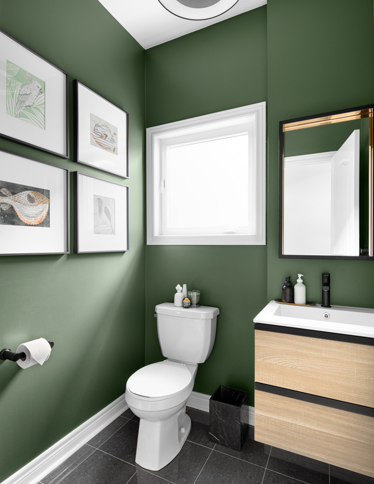 Inspiration for a mid-sized contemporary powder room in Toronto with flat-panel cabinets, light wood cabinets, a two-piece toilet, green walls, ceramic floors, solid surface benchtops, black floor, white benchtops and a floating vanity.