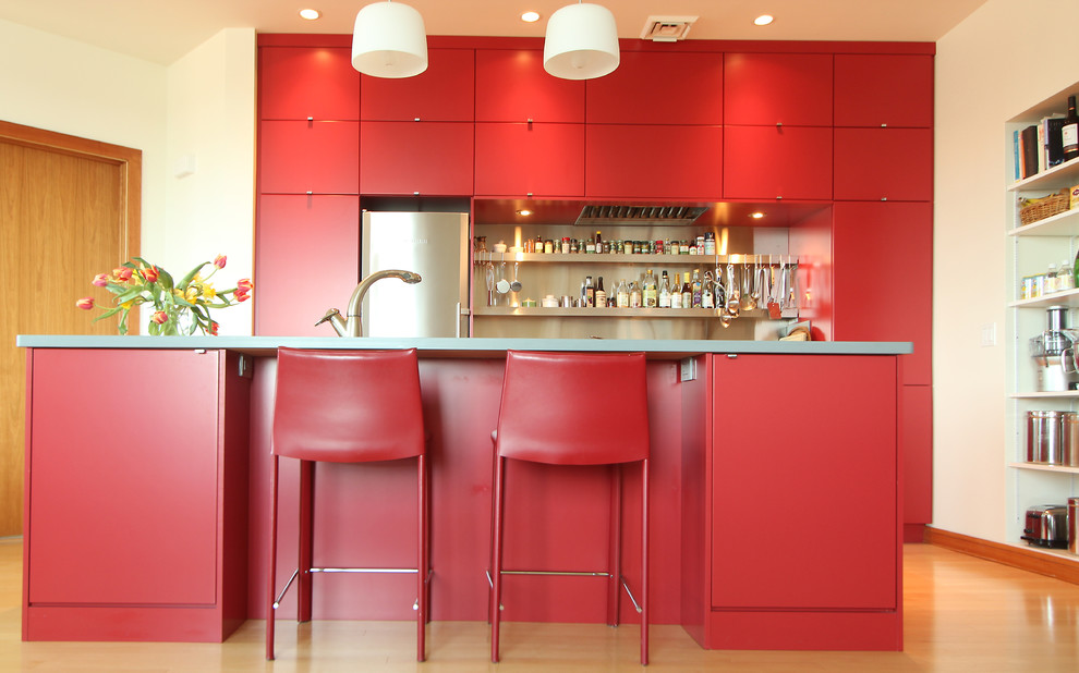 Inspiration for a small modern medium tone wood floor open concept kitchen remodel with an undermount sink, flat-panel cabinets, red cabinets, solid surface countertops, metal backsplash, stainless steel appliances and an island