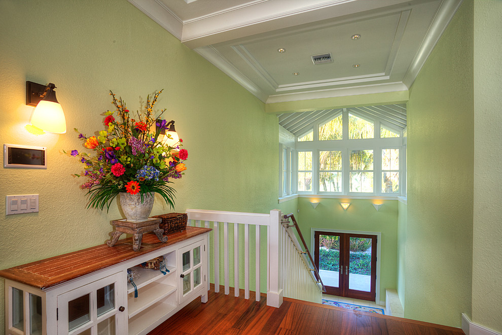 This is an example of a large tropical foyer in Tampa with green walls, a double front door, a glass front door and medium hardwood floors.