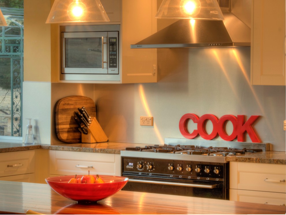 Large country u-shaped kitchen pantry in Other with an undermount sink, shaker cabinets, white cabinets, wood benchtops, metallic splashback, glass sheet splashback, black appliances, terra-cotta floors and with island.