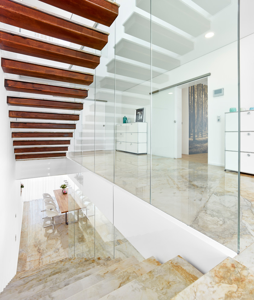 Photo of a mid-sized contemporary wood straight staircase in Other with glass railing.