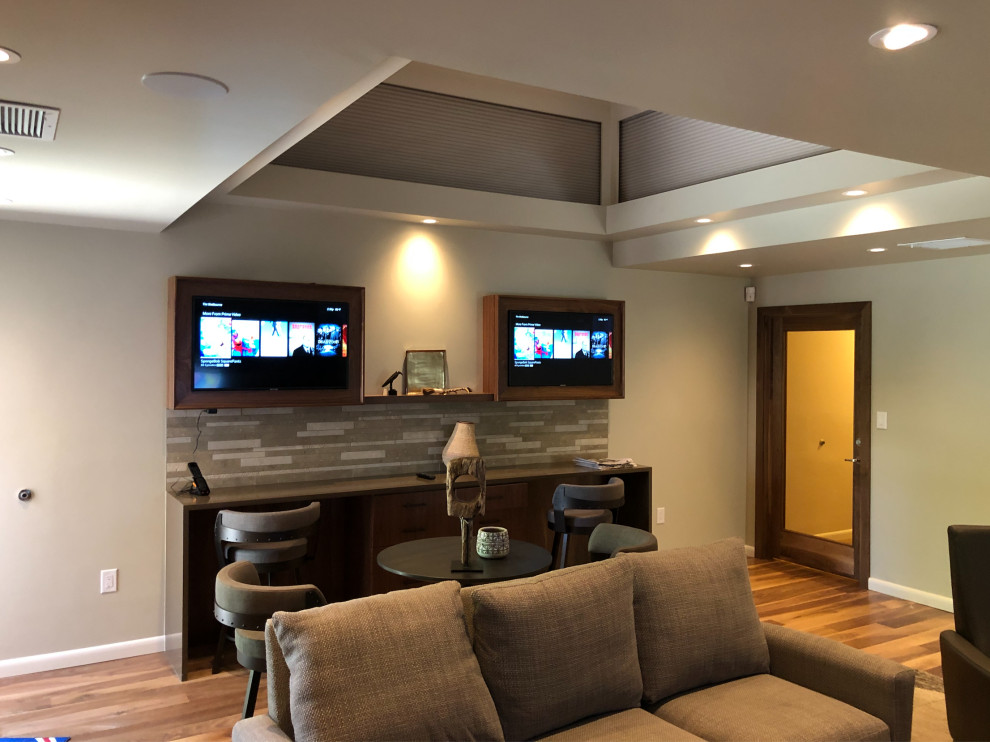 Home theater - mid-sized modern enclosed medium tone wood floor and brown floor home theater idea in Albuquerque with gray walls and a media wall