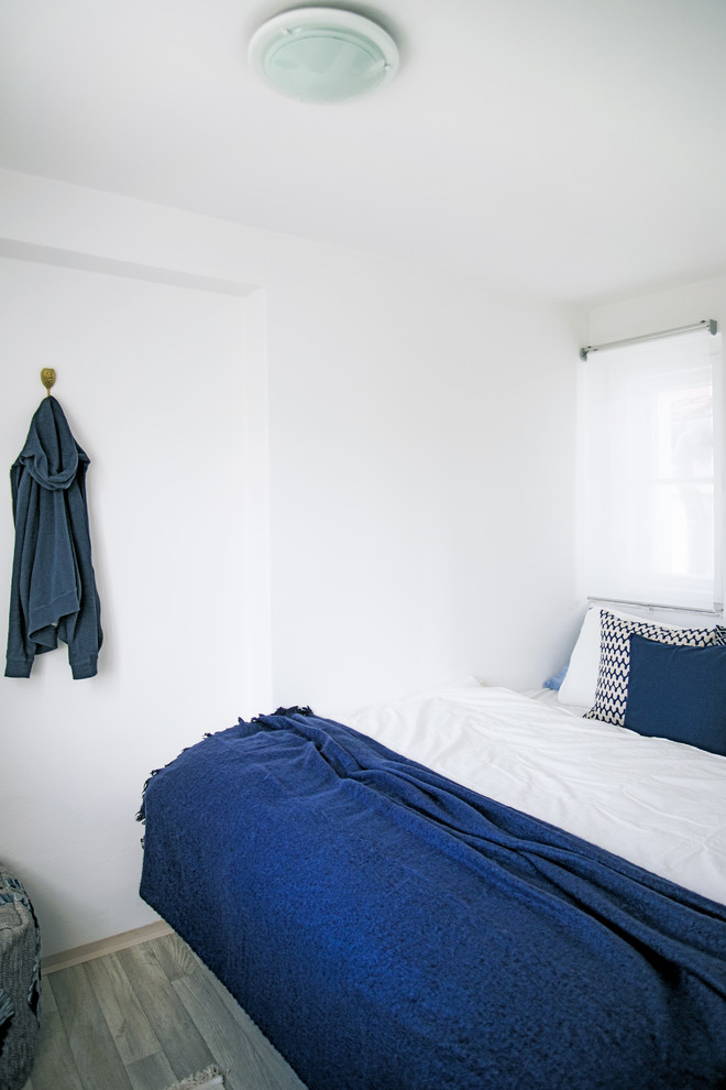 Ejemplo de habitación de invitados tradicional renovada pequeña con paredes blancas, suelo laminado y suelo gris