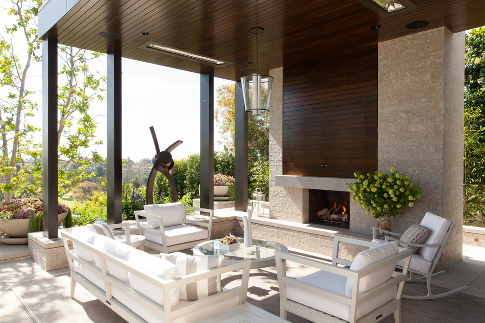 This is an example of a contemporary patio in Los Angeles with a roof extension and with fireplace.