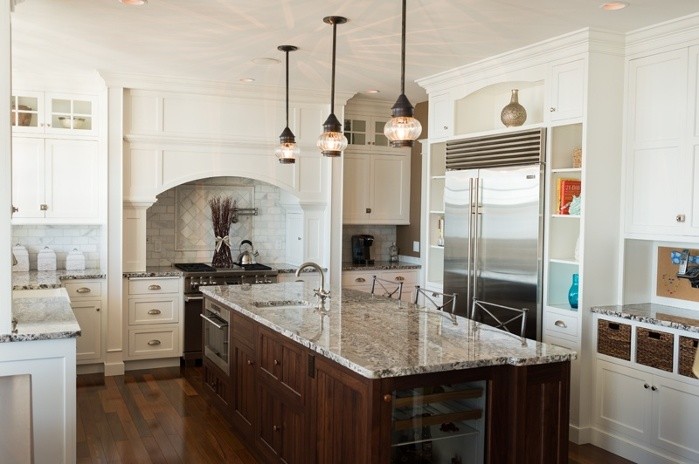 This is an example of a large traditional eat-in kitchen in Boston with an undermount sink, raised-panel cabinets, white cabinets, white appliances, dark hardwood floors and with island.
