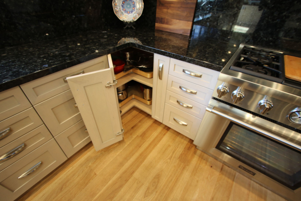 Bild på ett mellanstort vintage flerfärgad flerfärgat kök, med en rustik diskho, skåp i shakerstil, vita skåp, granitbänkskiva, svart stänkskydd, rostfria vitvaror, ljust trägolv, en köksö och brunt golv