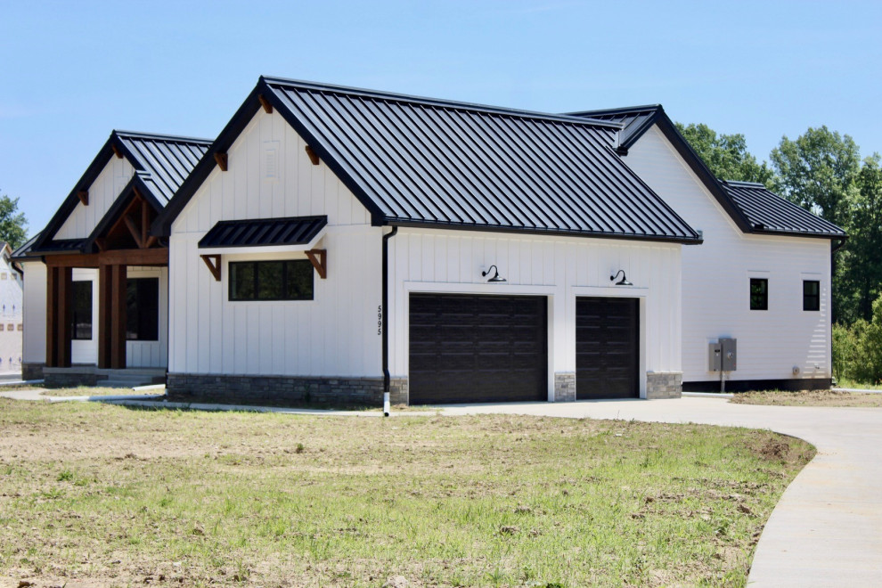 На фото: одноэтажный, белый частный загородный дом в стиле кантри с облицовкой из ЦСП, металлической крышей, черной крышей и отделкой доской с нащельником с