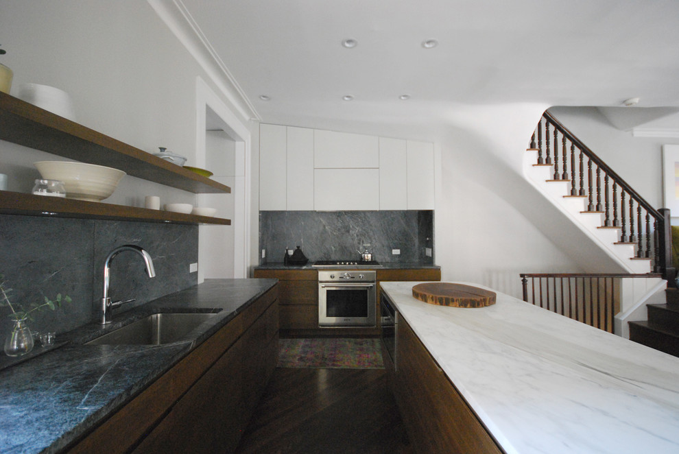 This is an example of a small l-shaped eat-in kitchen in New York with a single-bowl sink, flat-panel cabinets, dark wood cabinets, soapstone benchtops, grey splashback, stone slab splashback, stainless steel appliances, medium hardwood floors, with island and brown floor.