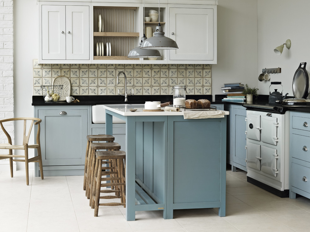 This is an example of a large country l-shaped open plan kitchen in Cheshire with a farmhouse sink, shaker cabinets, blue cabinets, quartzite benchtops, terra-cotta splashback, white appliances, limestone floors and with island.
