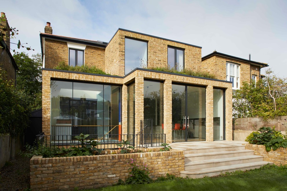 Photo of a mid-sized contemporary three-storey brick brown house exterior in London with a flat roof and a mixed roof.