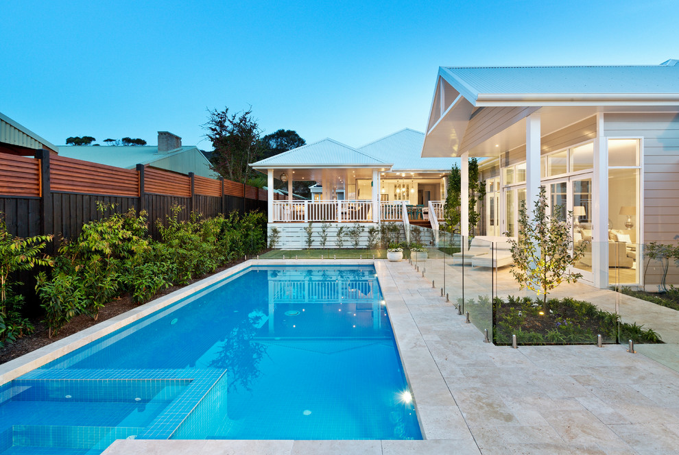 Large beach style backyard rectangular pool in Melbourne with a pool house and natural stone pavers.