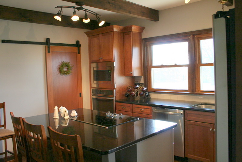 Mid-sized transitional l-shaped medium tone wood floor kitchen photo with an undermount sink, recessed-panel cabinets, medium tone wood cabinets, granite countertops, white backsplash, ceramic backsplash, stainless steel appliances and an island