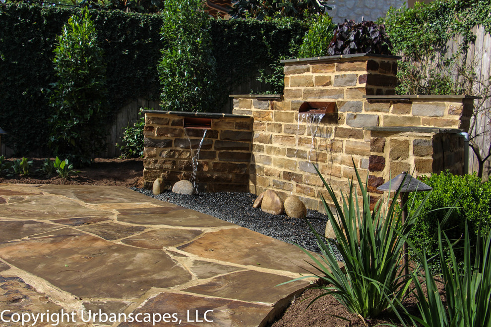 Backyard patio in Houston with a water feature, natural stone pavers and no cover.