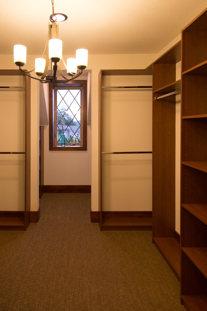 This is an example of a mid-sized traditional gender-neutral walk-in wardrobe in Portland with open cabinets, medium wood cabinets and carpet.