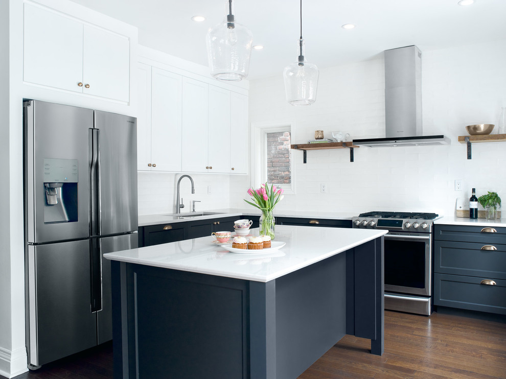 Inspiration for a mid-sized transitional l-shaped medium tone wood floor enclosed kitchen remodel in Toronto with an undermount sink, recessed-panel cabinets, blue cabinets, quartz countertops, white backsplash, subway tile backsplash, stainless steel appliances and an island