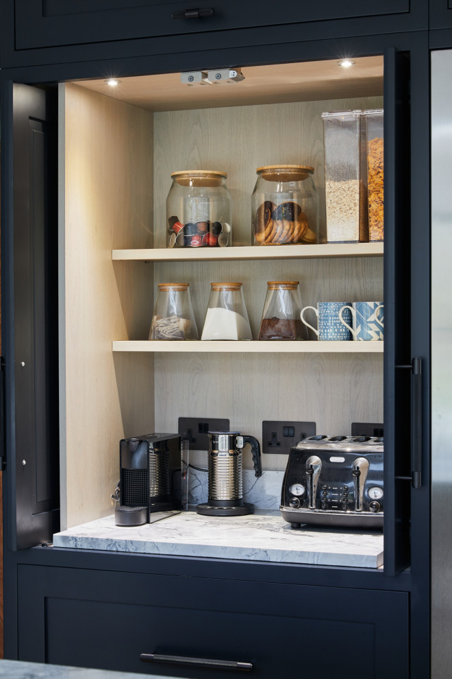 Idée de décoration pour une grande cuisine américaine tradition en L avec un placard avec porte à panneau encastré, des portes de placard noires et îlot.