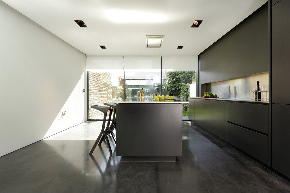 Mid-sized contemporary single-wall separate kitchen in London with a drop-in sink, flat-panel cabinets, black cabinets, solid surface benchtops, metallic splashback, stainless steel appliances, concrete floors and with island.