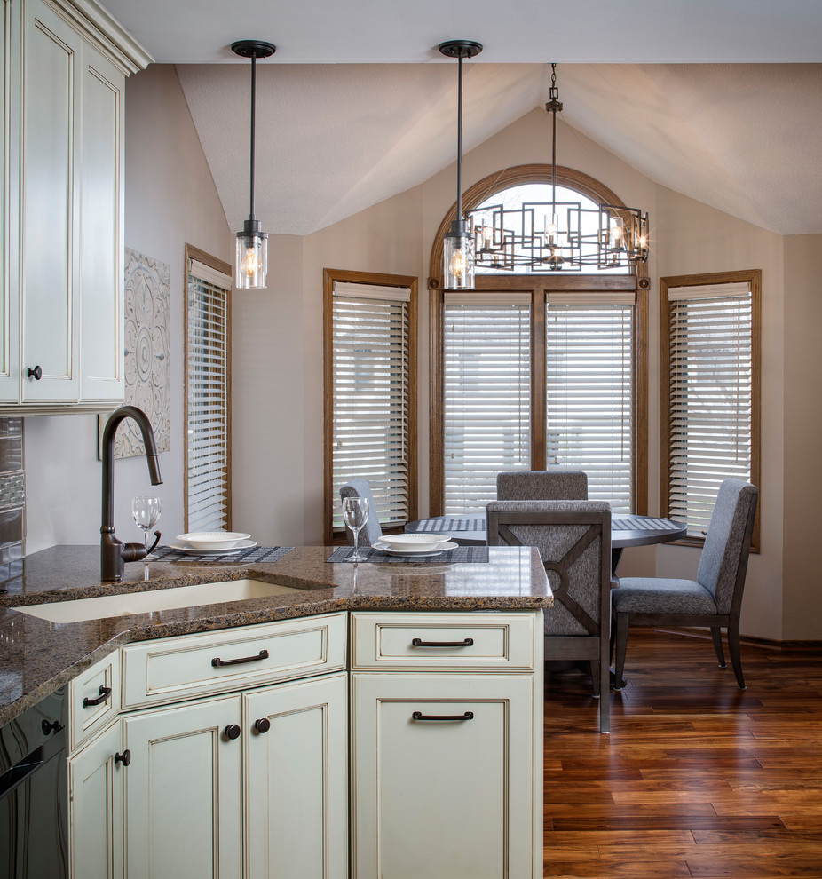 Inspiration for a mid-sized traditional l-shaped eat-in kitchen in Omaha with a single-bowl sink, glass-front cabinets, white cabinets, quartz benchtops, beige splashback, subway tile splashback, stainless steel appliances, medium hardwood floors, a peninsula, brown floor and brown benchtop.