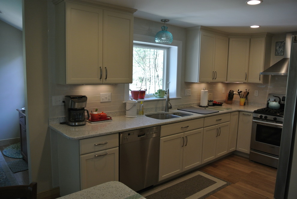 Eat-in kitchen - transitional l-shaped medium tone wood floor eat-in kitchen idea in Boston with an undermount sink, shaker cabinets, white cabinets, recycled glass countertops, white backsplash, subway tile backsplash, stainless steel appliances, a peninsula and white countertops
