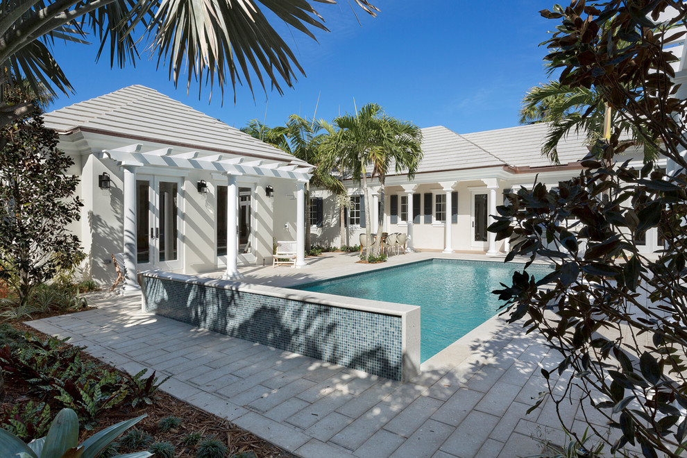 Photo of a large tropical backyard rectangular lap pool in Miami with concrete pavers.