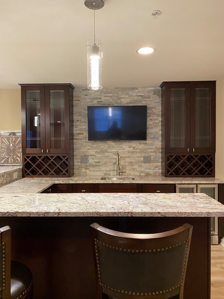 Mid-sized trendy u-shaped vinyl floor and multicolored floor wet bar photo in Baltimore with an undermount sink, shaker cabinets, brown cabinets, quartz countertops, multicolored backsplash, stone tile backsplash and multicolored countertops