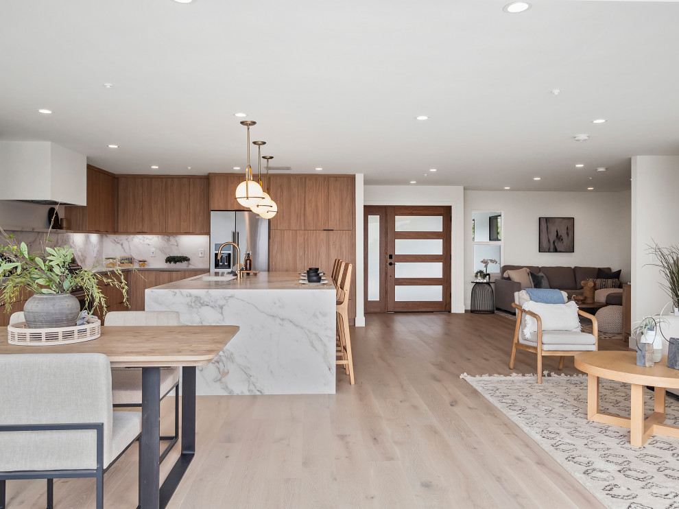 Photo of a large contemporary l-shaped open plan kitchen in Orange County with an undermount sink, flat-panel cabinets, medium wood cabinets, marble benchtops, white splashback, marble splashback, stainless steel appliances, light hardwood floors, with island, beige floor and yellow benchtop.