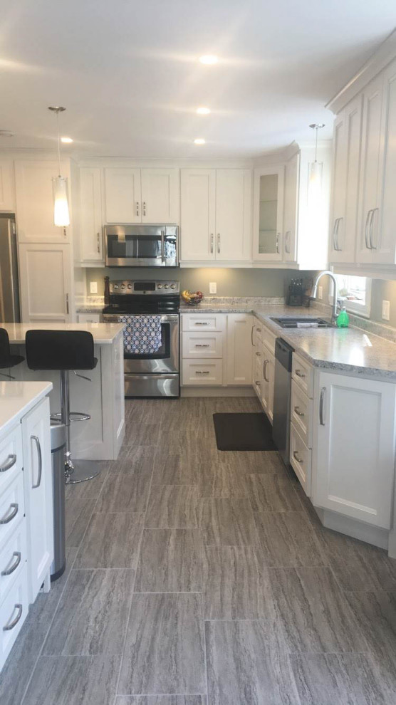 Example of a mid-sized transitional u-shaped porcelain tile and gray floor eat-in kitchen design with an undermount sink, recessed-panel cabinets, white cabinets, quartz countertops, stainless steel appliances, an island and white countertops