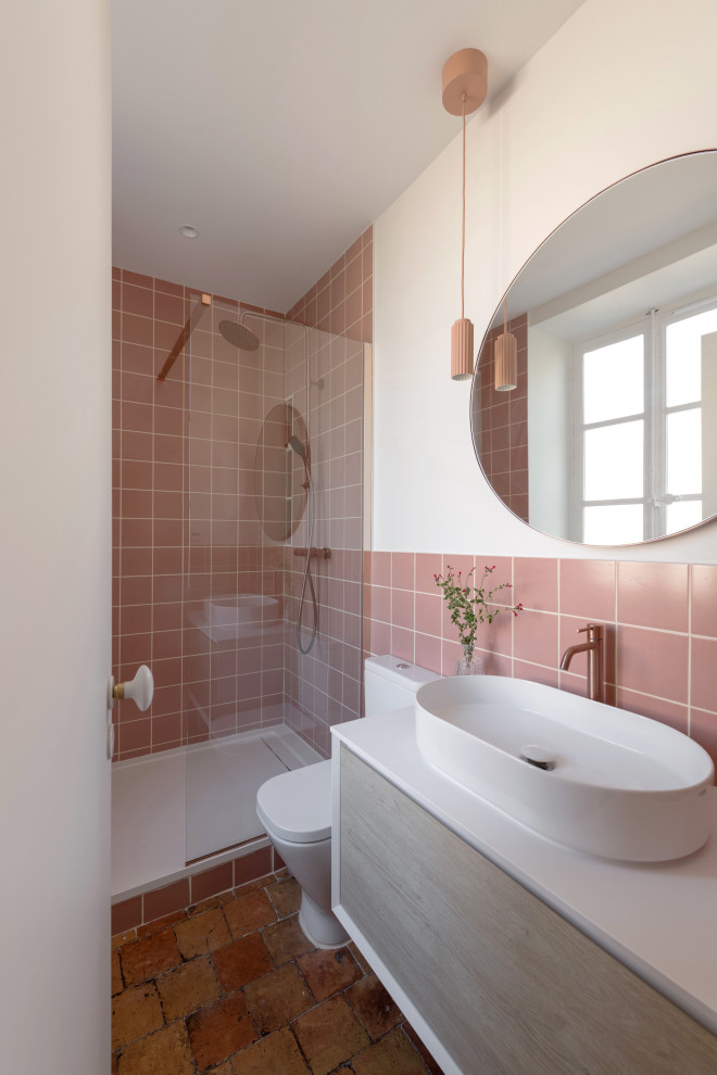 Идея дизайна: узкая и длинная ванная комната среднего размера в стиле неоклассика (современная классика) с открытым душем, унитазом-моноблоком, розовой плиткой, керамической плиткой, розовыми стенами, полом из терракотовой плитки, душевой кабиной, настольной раковиной, столешницей из ламината, белой столешницей и тумбой под одну раковину