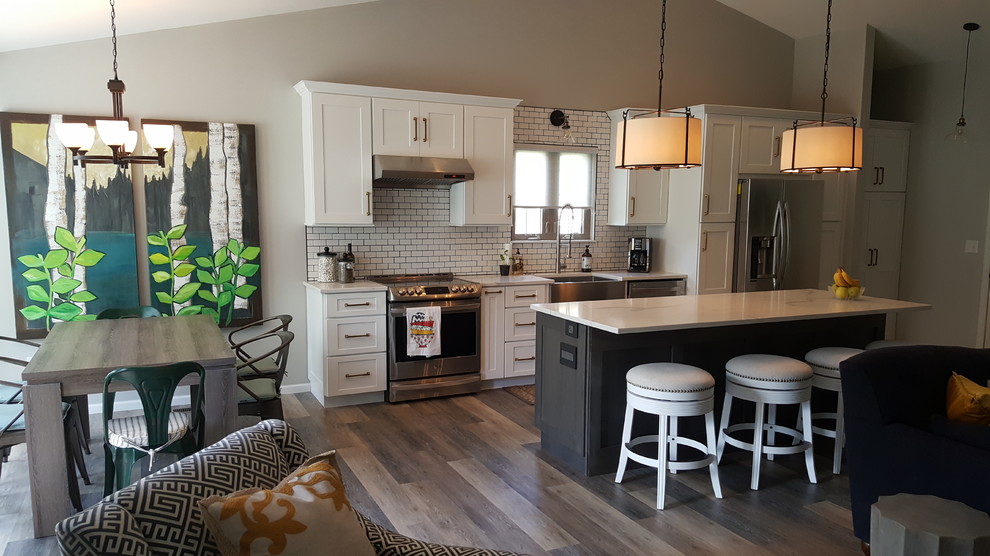 Inspiration for a small modern galley open plan kitchen in Cedar Rapids with a farmhouse sink, shaker cabinets, white cabinets, quartz benchtops, white splashback, subway tile splashback, stainless steel appliances, vinyl floors and with island.
