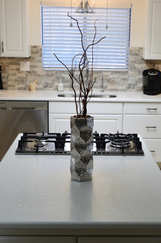 Example of a mid-sized transitional l-shaped porcelain tile enclosed kitchen design in Albuquerque with an undermount sink, raised-panel cabinets, white cabinets, quartz countertops, beige backsplash, porcelain backsplash, stainless steel appliances and no island