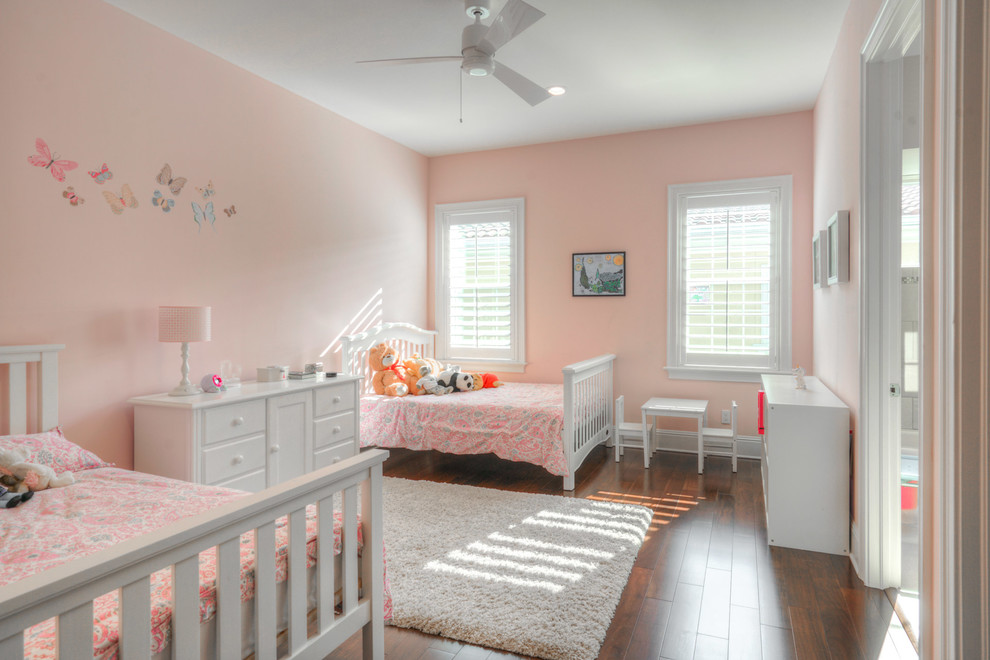 This is an example of a large transitional kids' bedroom for kids 4-10 years old and girls in Tampa with pink walls, medium hardwood floors and brown floor.