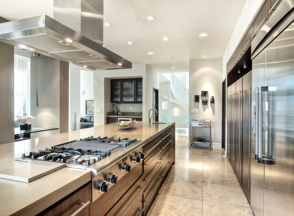 Inspiration for a large modern galley separate kitchen in Orange County with an undermount sink, flat-panel cabinets, dark wood cabinets, quartzite benchtops, stainless steel appliances, limestone floors, with island and beige floor.