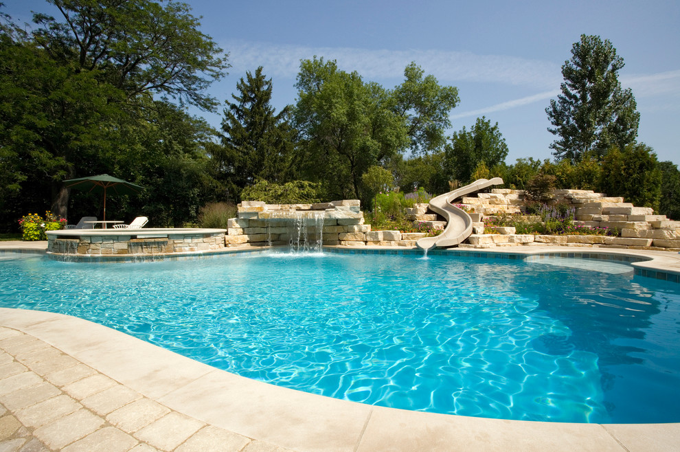 Design ideas for an expansive country backyard custom-shaped natural pool in Chicago with a water slide and concrete pavers.