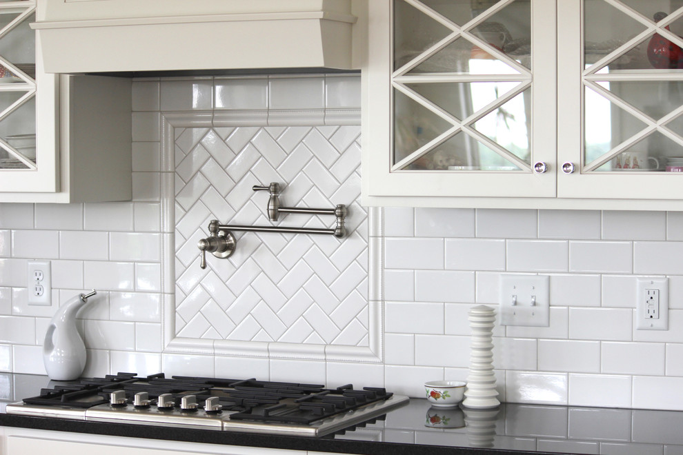 Kitchen - large transitional kitchen idea in Cedar Rapids with glass-front cabinets, white cabinets, quartzite countertops, white backsplash, subway tile backsplash and stainless steel appliances