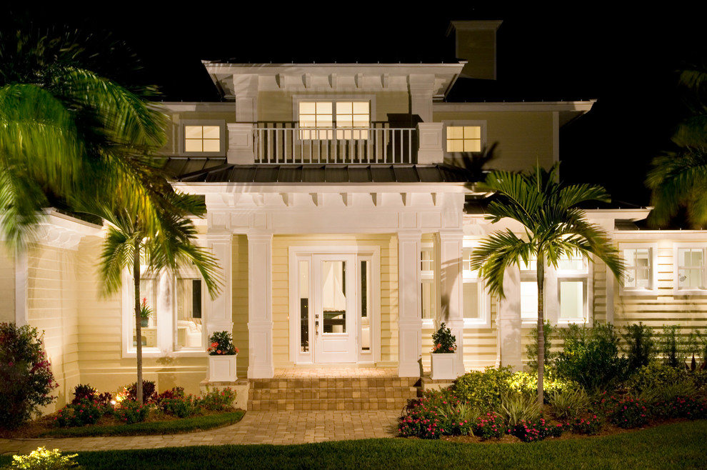 This is an example of a large tropical two-storey yellow exterior in Miami with wood siding.
