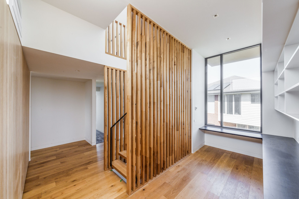 This is an example of a large contemporary wood floating staircase in Geelong with metal railing and wood walls.