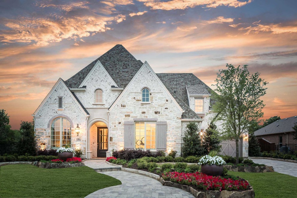 Inspiration for a traditional two-storey beige house exterior in Dallas with stone veneer and a shingle roof.
