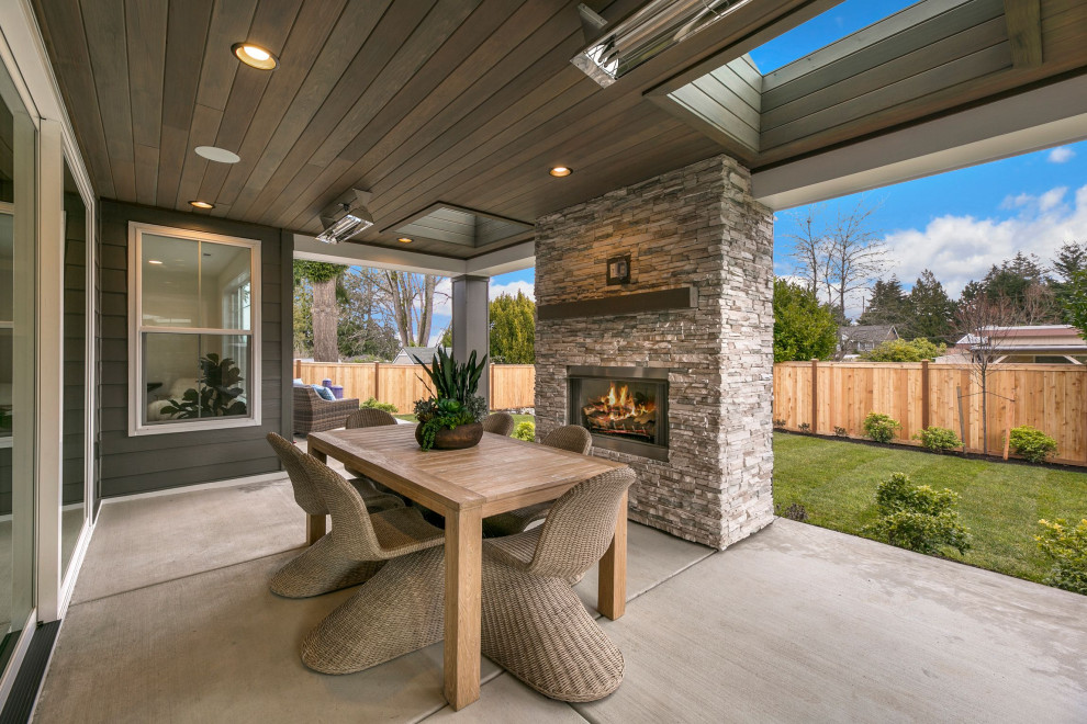 Inspiration for a large farmhouse back patio in Seattle with a fireplace, concrete slabs and a roof extension.
